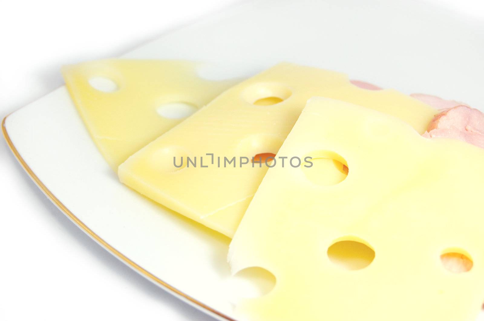 Slices of cheese with holes on plate over white