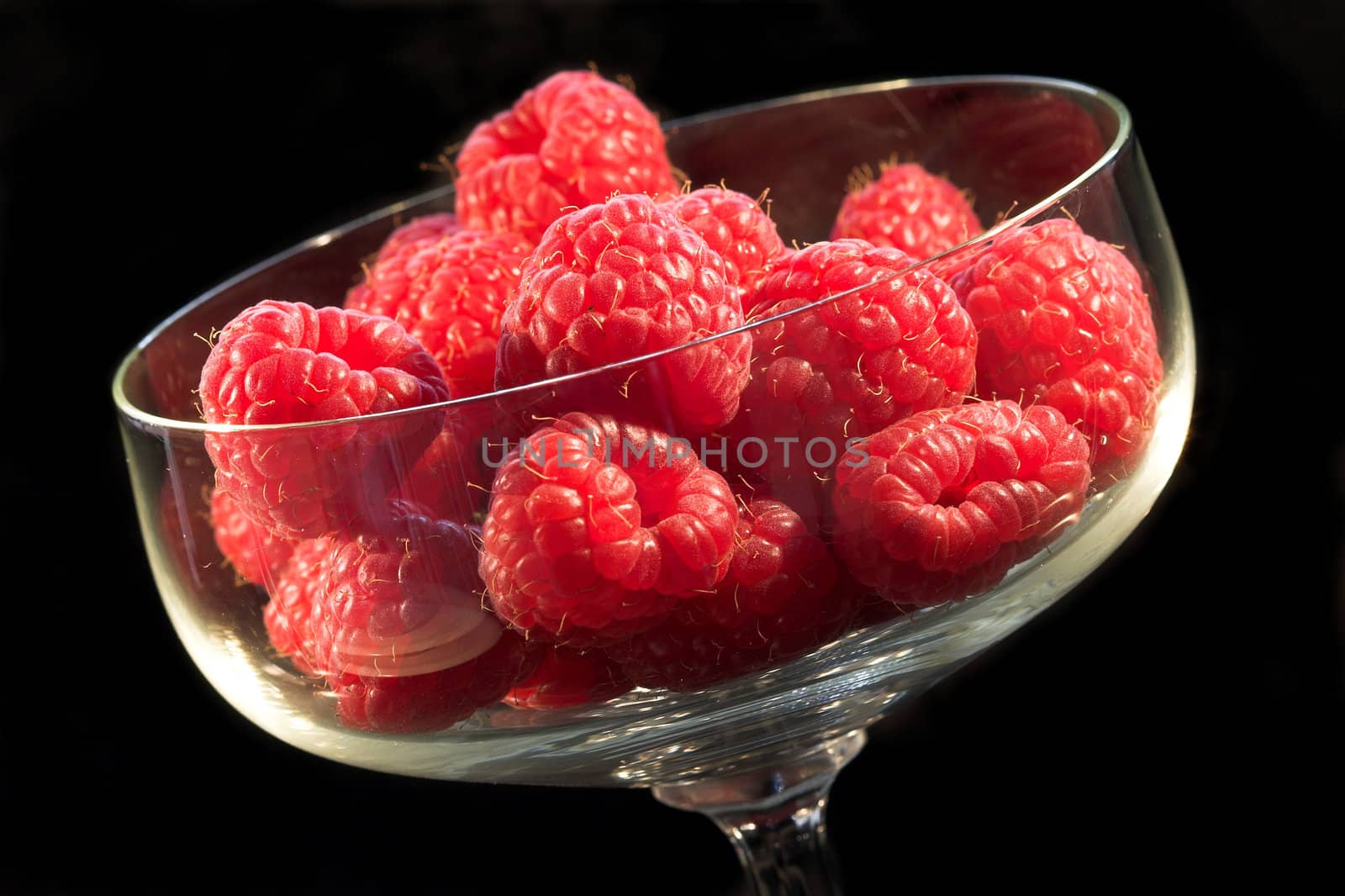 Bowl of fresh raspberries on black background
