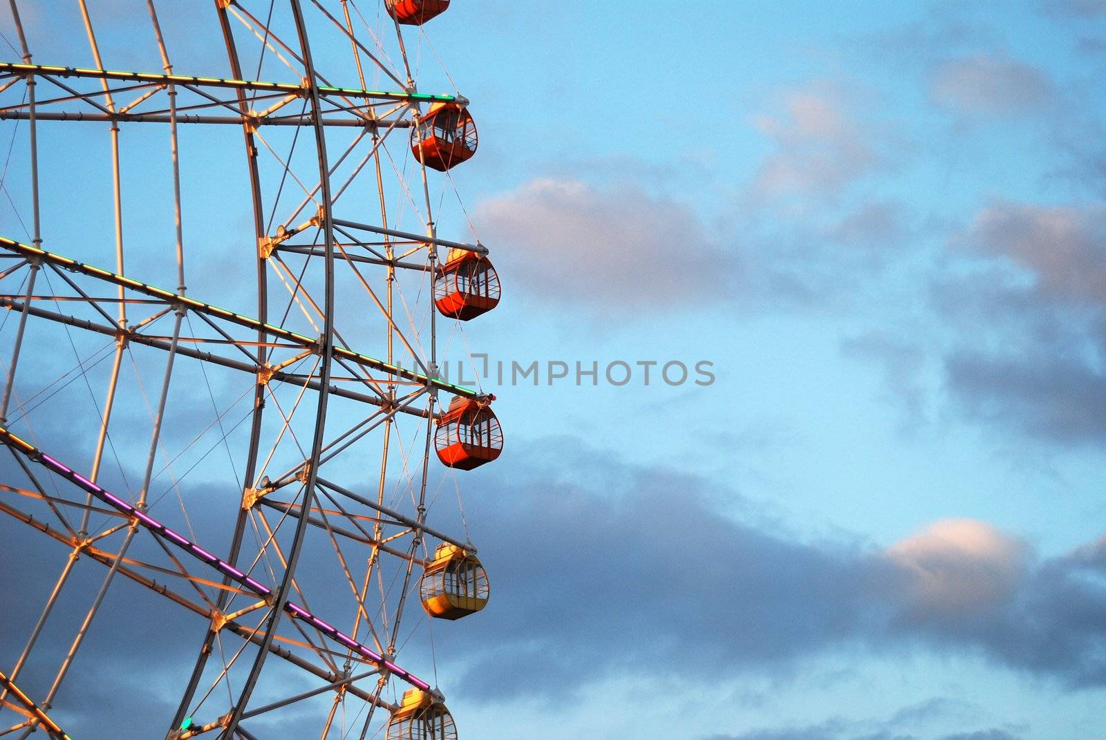 Section of ferris wheel against blue cloudy sky
