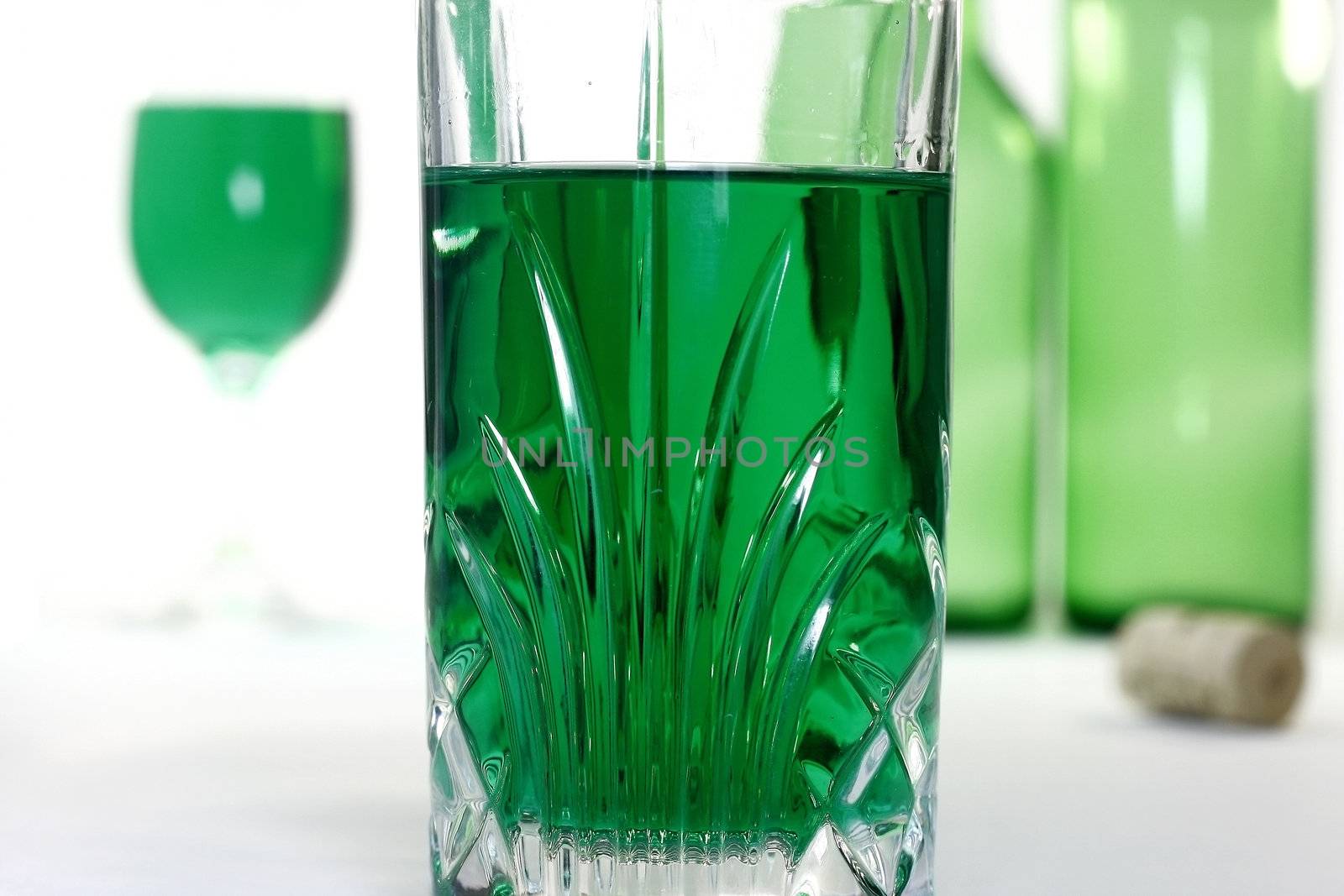 Glass with green wine and green wine background