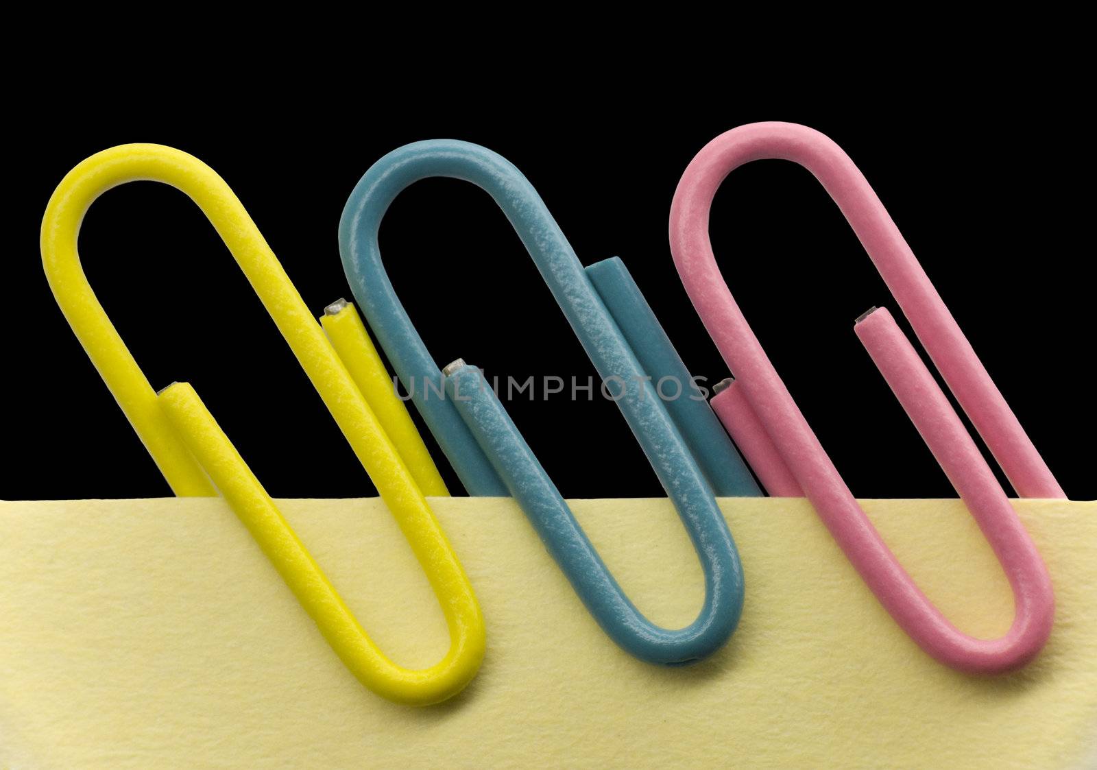 Paperclips on a yellow note with black background