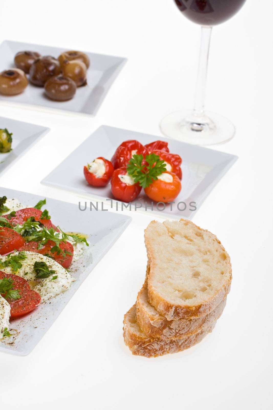 antipasti misti and bread on white plates by bernjuer