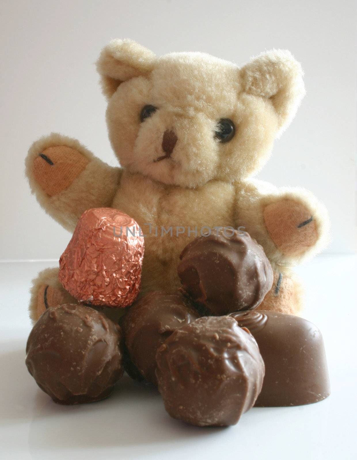 teddy with a pile of chocolates in front of it