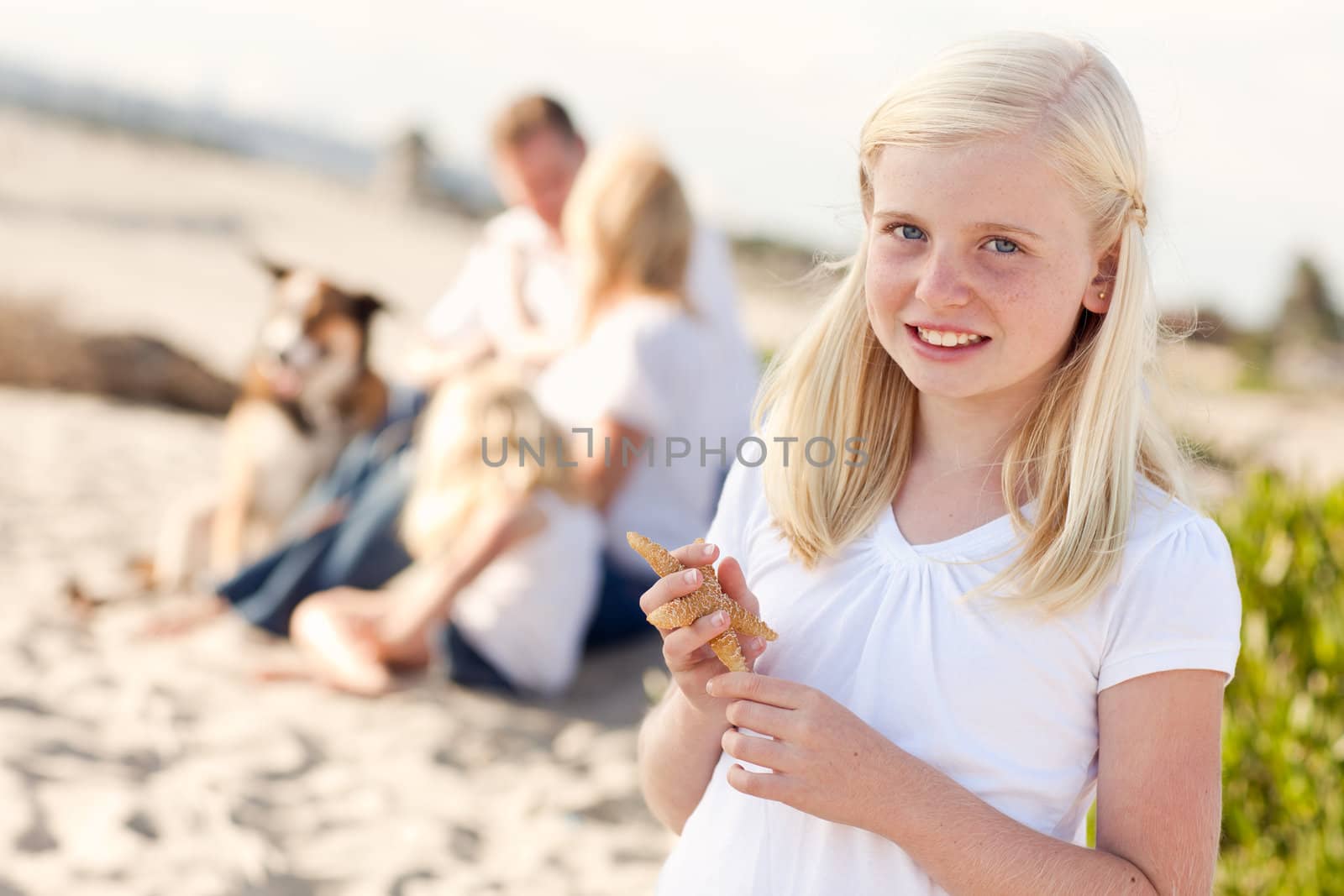 Adorable Little Blonde Girl with Starfish at The Beach.
