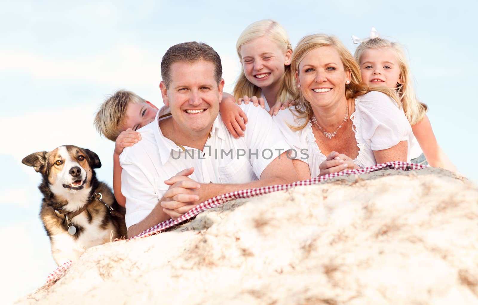 Happy Caucasian Family and Dog Portrait at the Beach One Sunny Afternoon.