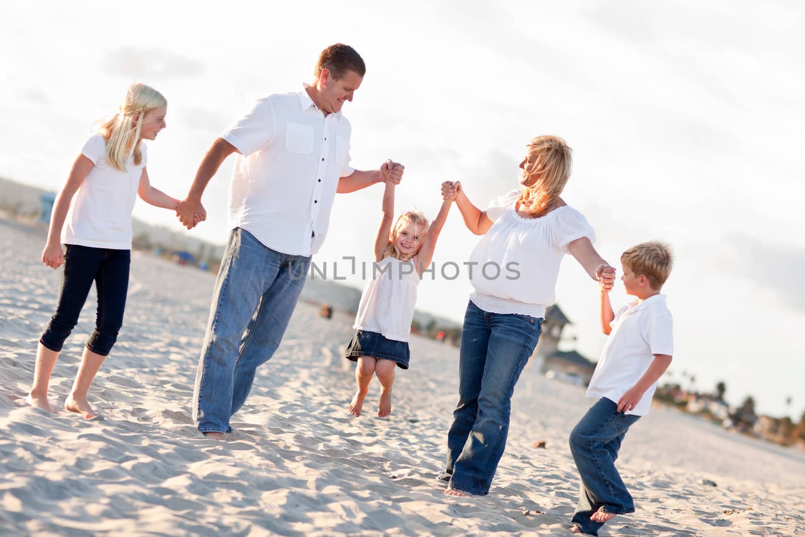 Adorable Little Girl Swinging with Her Parents and Family at the Beach.