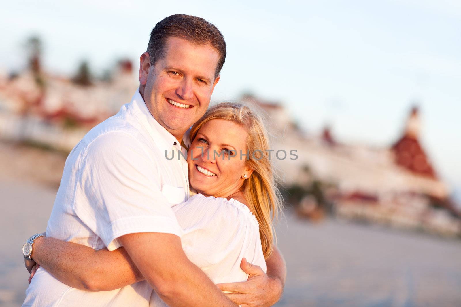 Attractive Caucasian Couple Hugging at the Beach in Front of the Hotel Del Coronado, San Diego, CA.