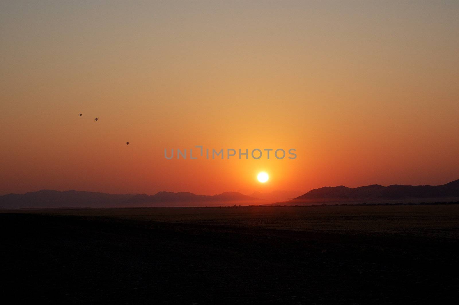 Balloons in the sky at sunrise by faberfoto