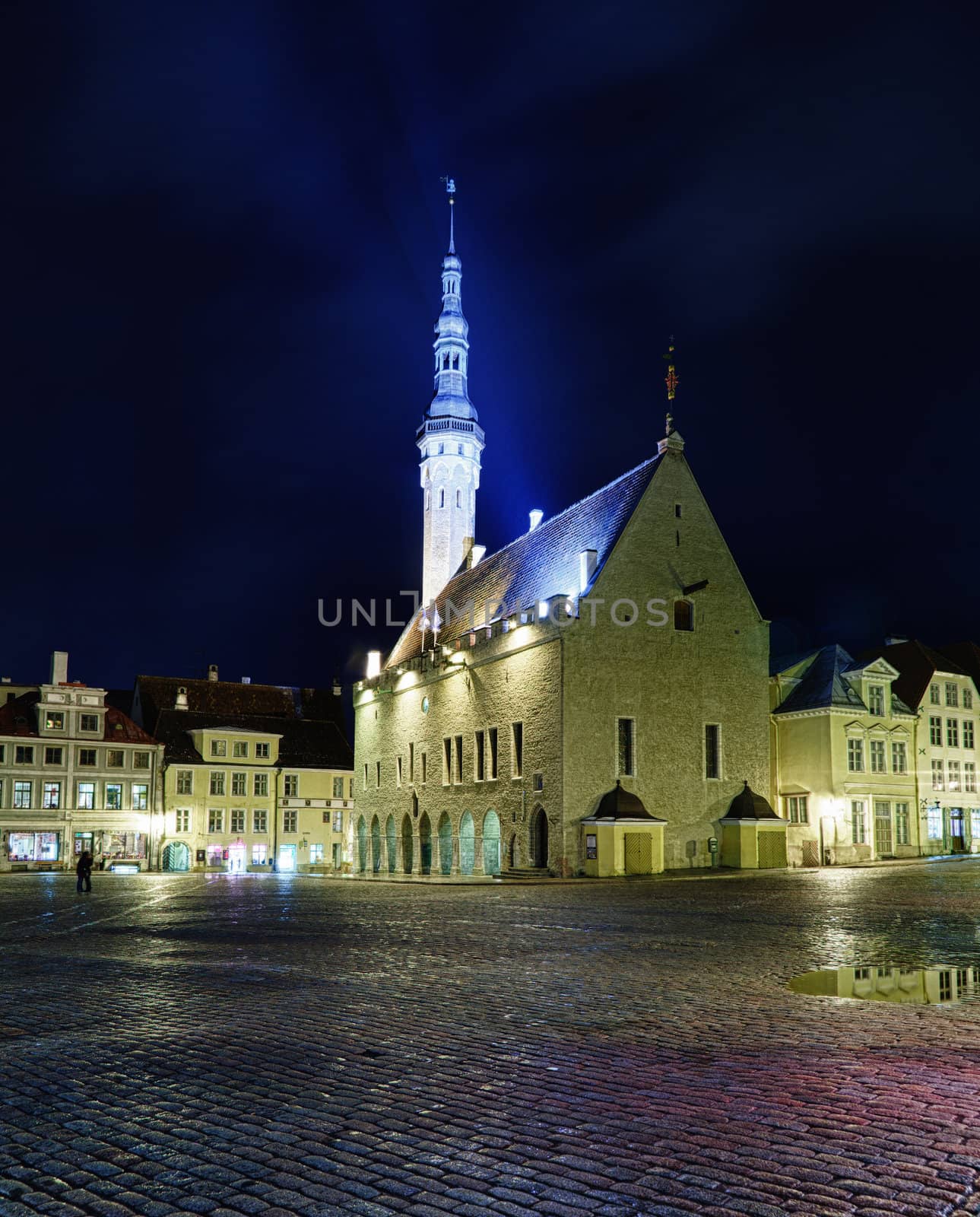 Tallinn town hall at night in Raekoya square showing the floodlit spire and tower of the hall