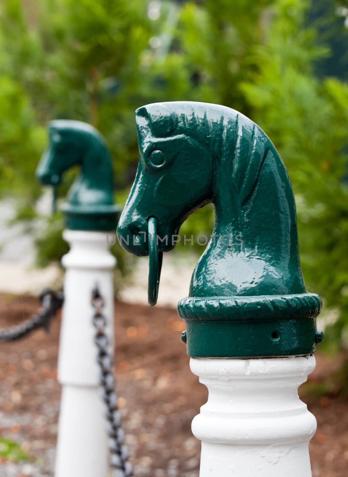 Green painted bollard for tying a horse to and shaped as a horse head