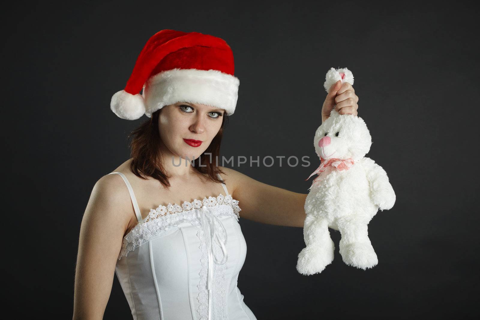 The woman in a Christmas cap holds in a hand a white rabbit on black