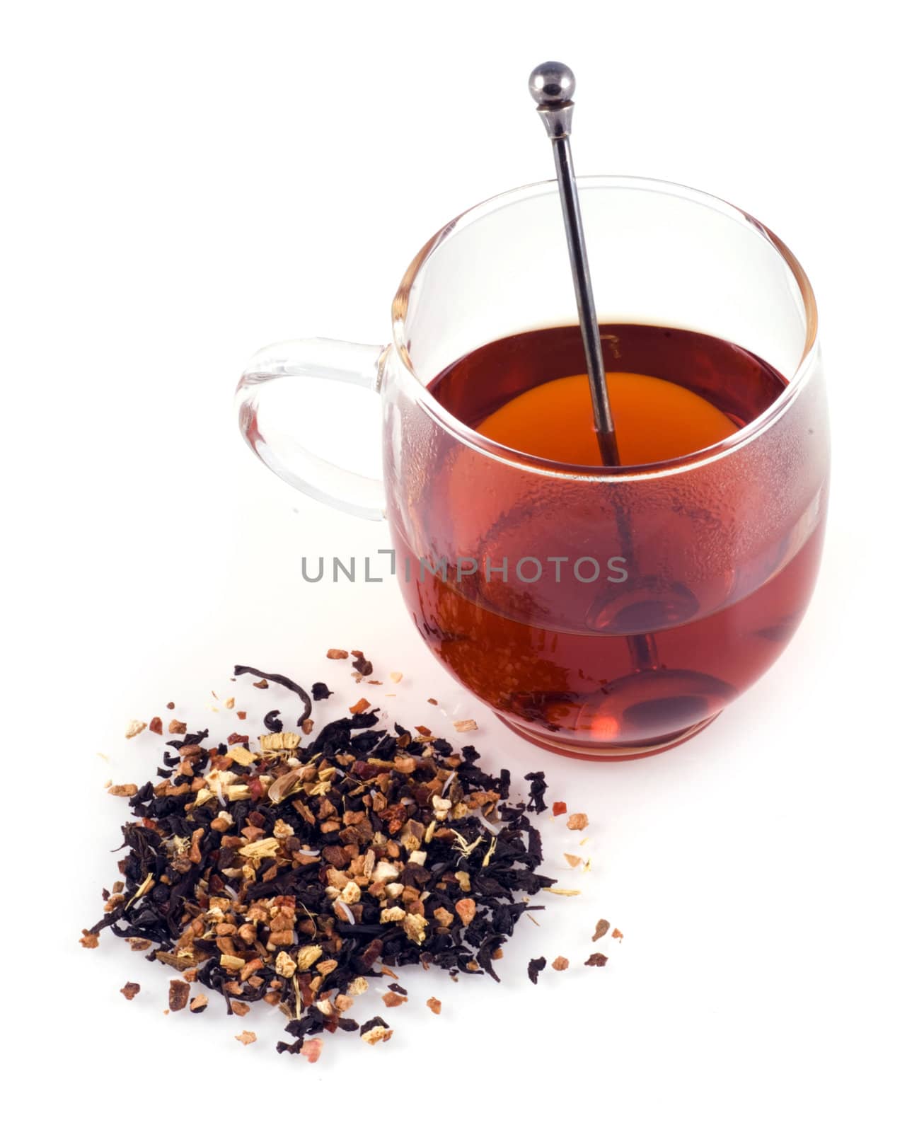 Glass of tea with some dried tea next to the glass on a white background.