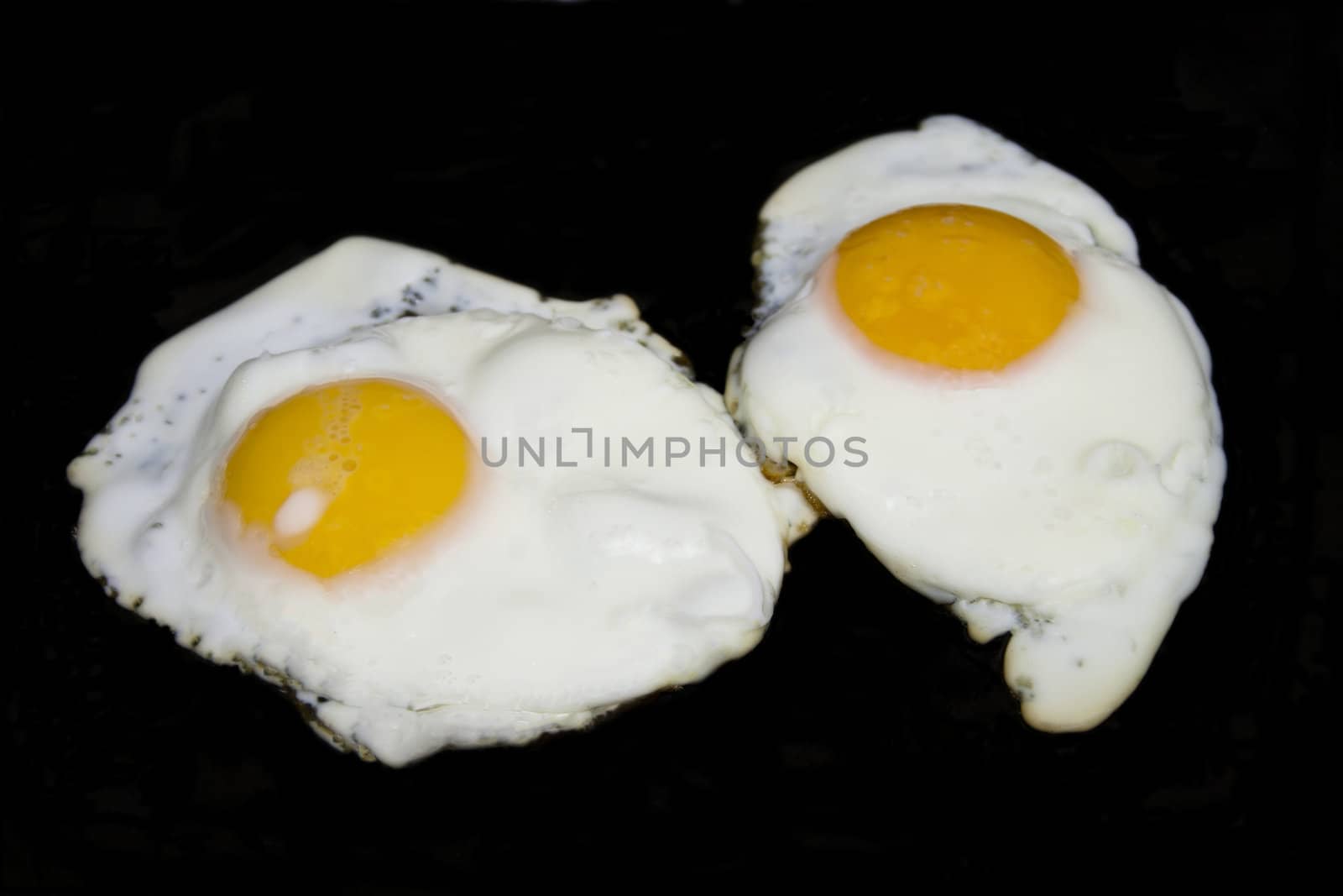 Fried eggs in isolated over black