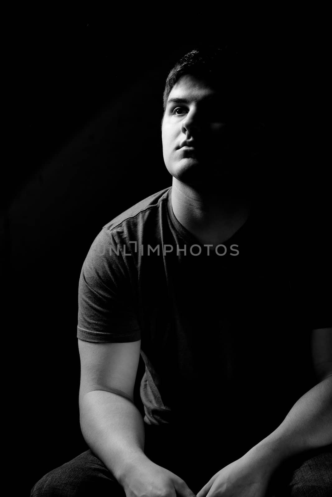 Low key portrait of a young  man in his late teens with a serious look on his face. 