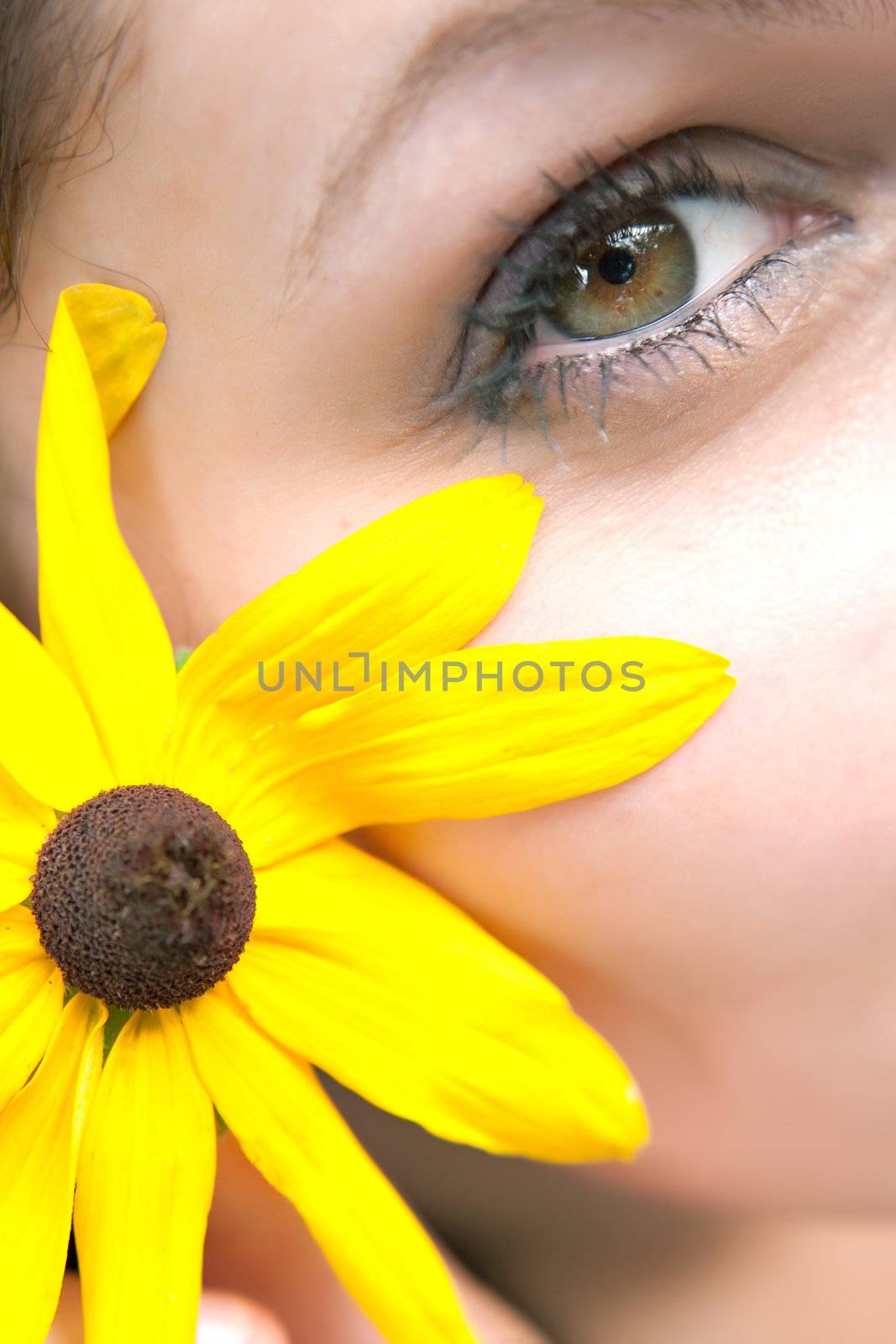 Close up of the face of a woman that is wearing a black eyed susan wildflower in her hair.  Shallow depth of field.