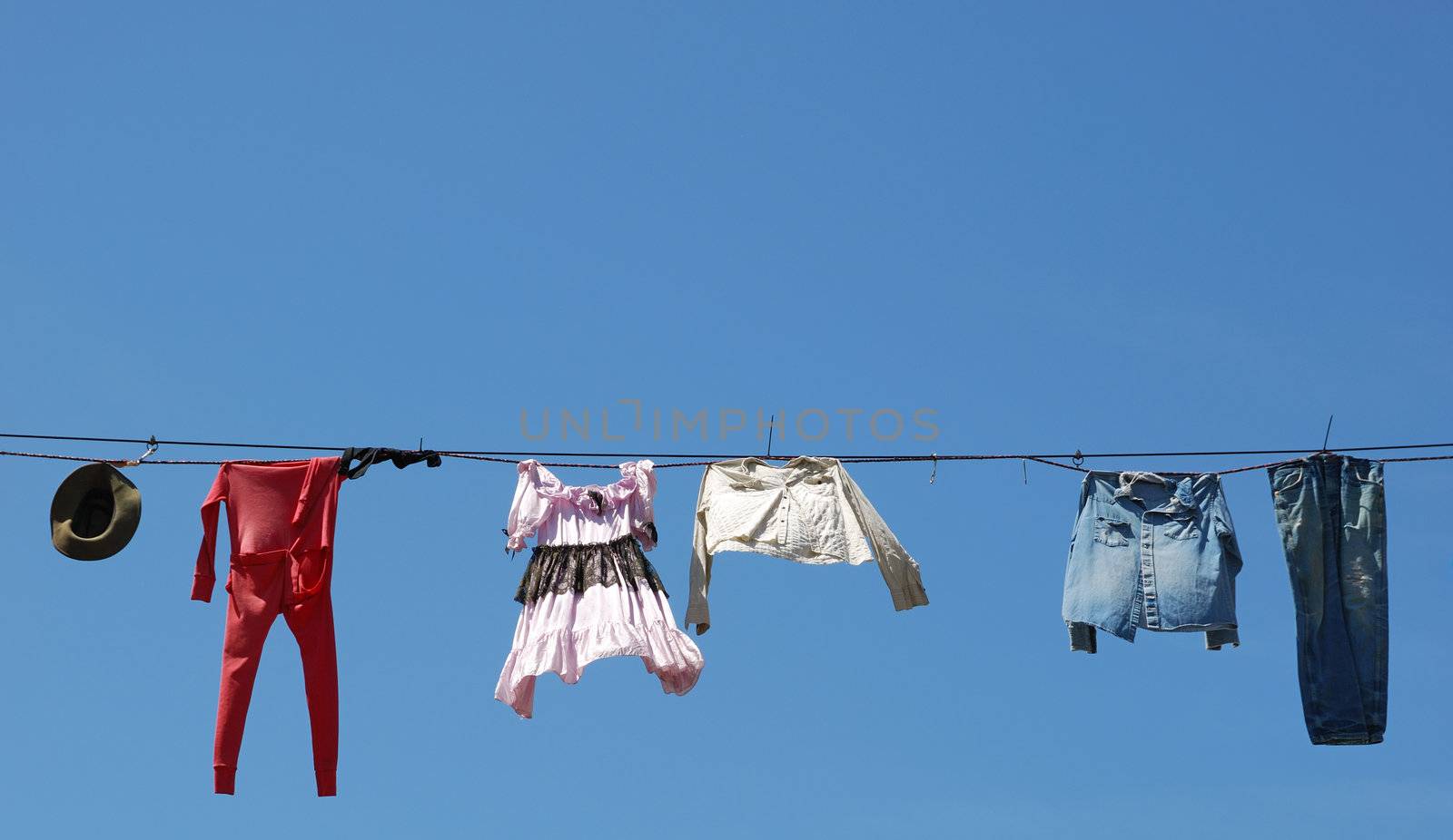 Old clothes hanging on the line against blue sky.