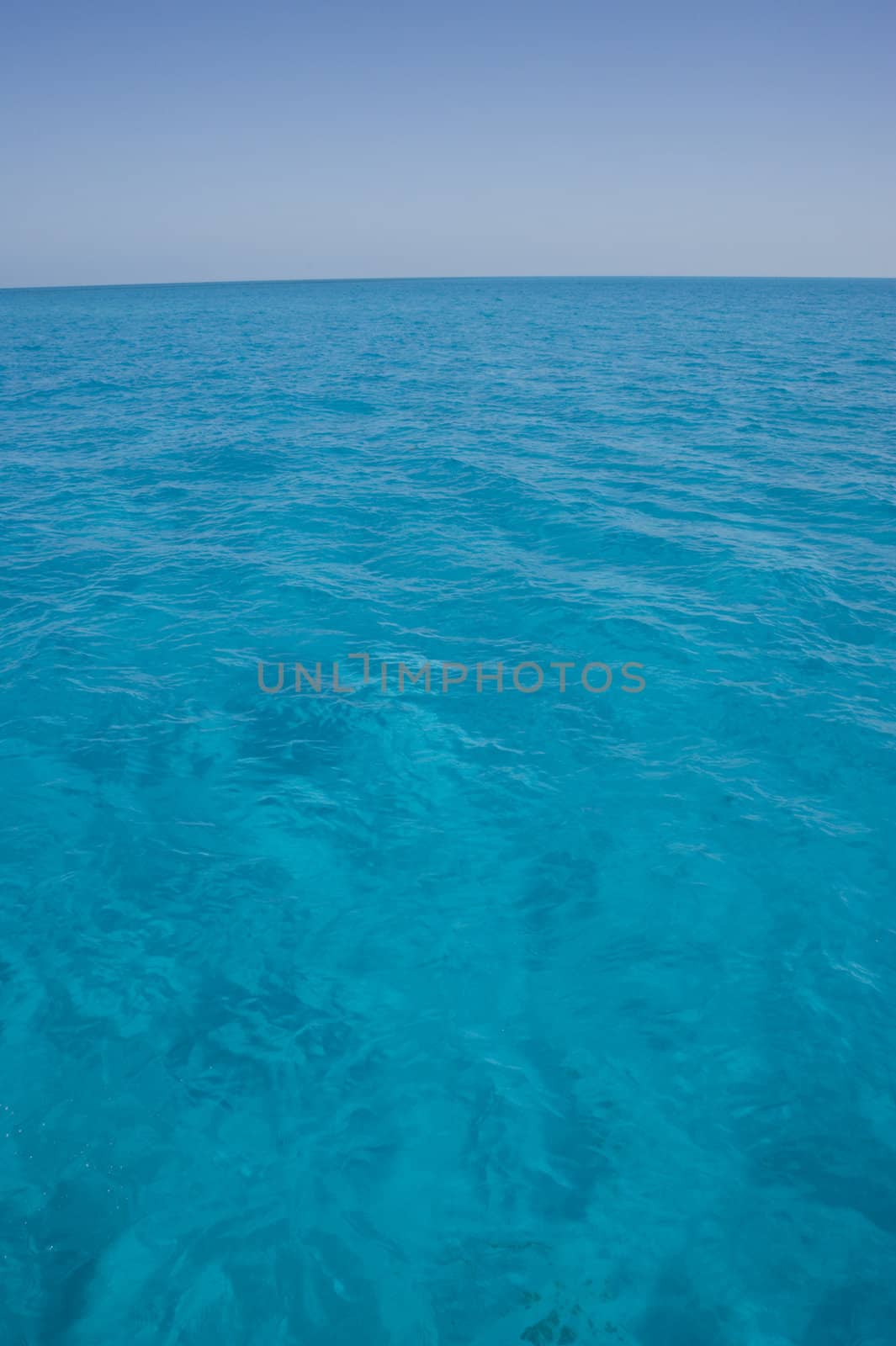 Portrait oriented background image of blue ocean water with a clear sky