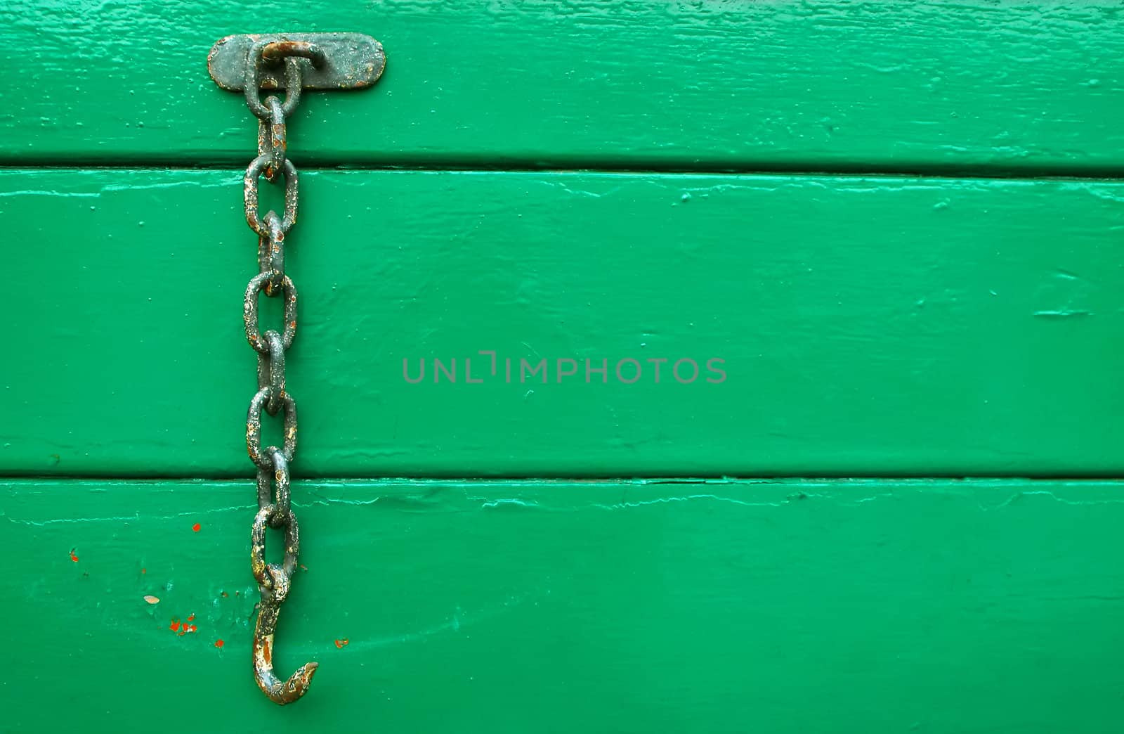 rusty hook and chain on green wood