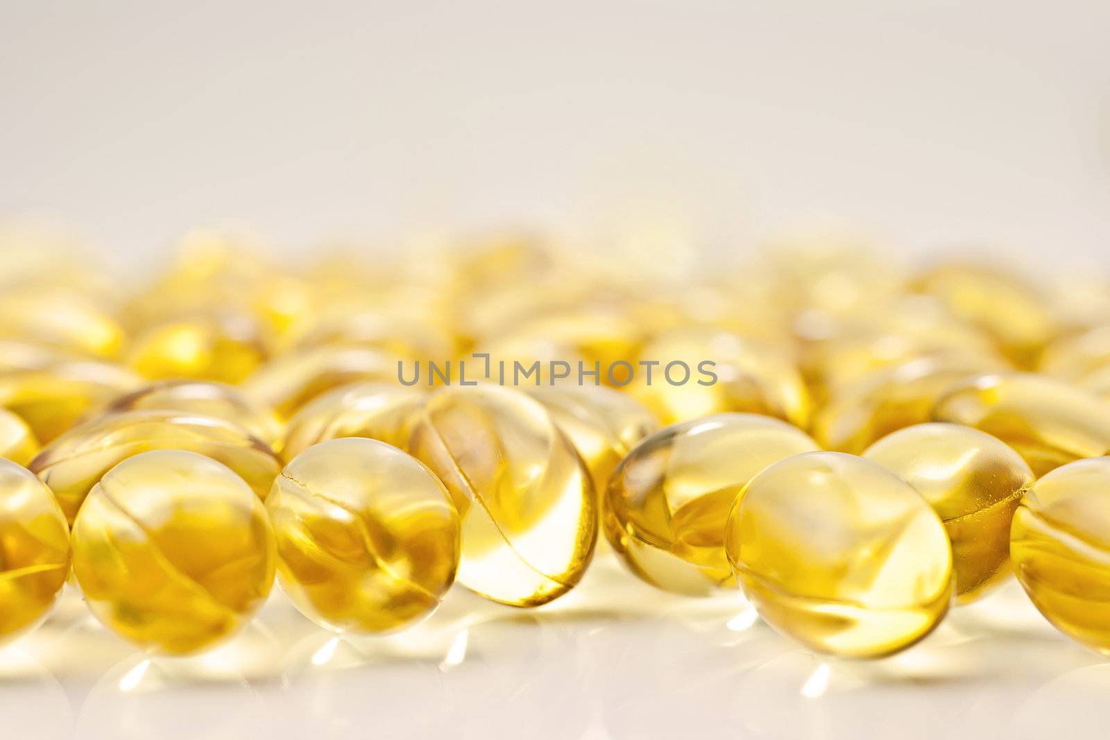 Nutritional supplement pills in warm colors and shallow depth of field. The yellow ones are vitamin E and cod liver oil.