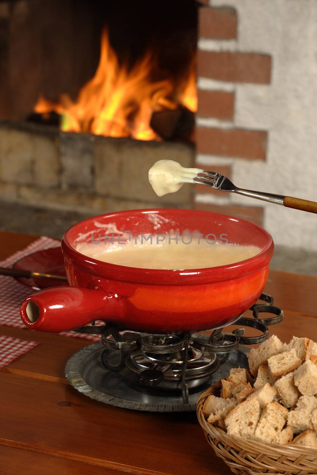 Bread being dipped into the melted cheese in the fondue bowl.