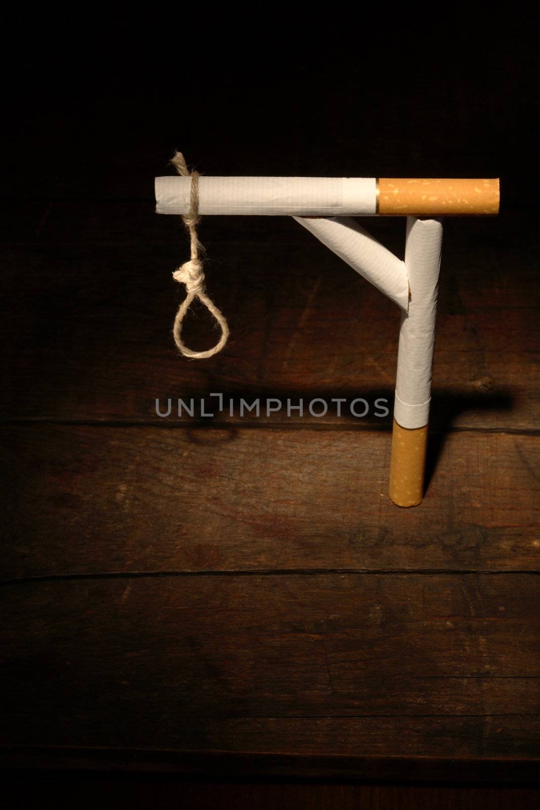 Gibbet made from cigarettes and rope on dark wooden background