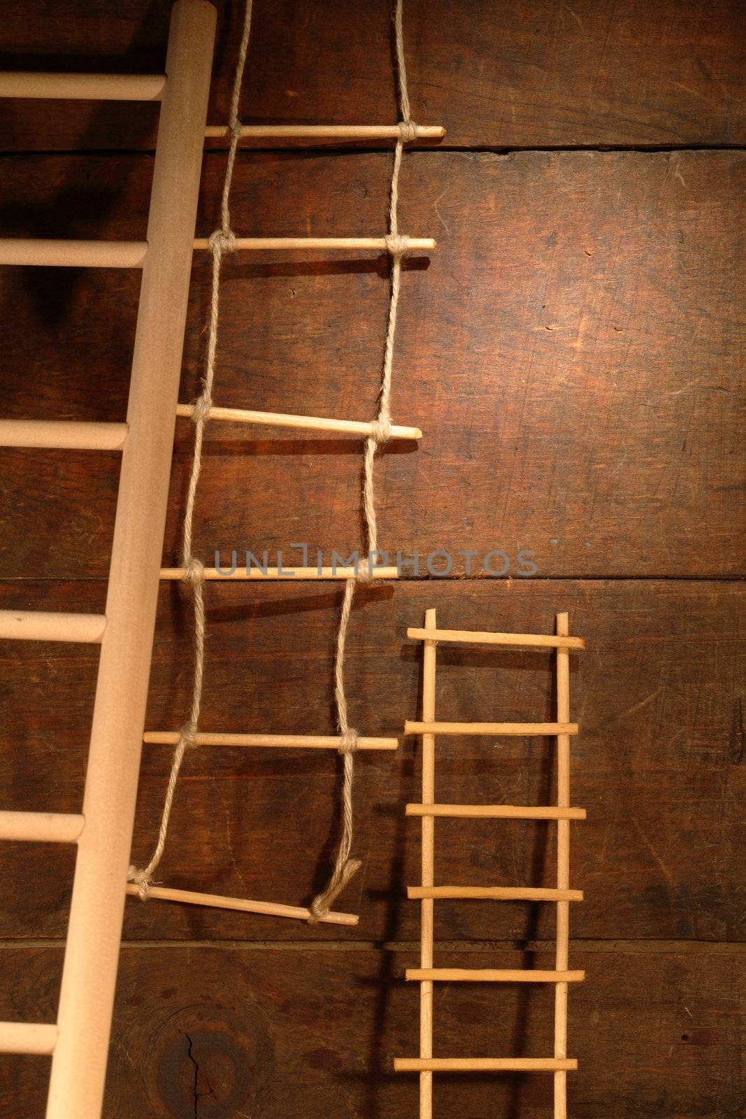 Three various ladders on old brown wooden background