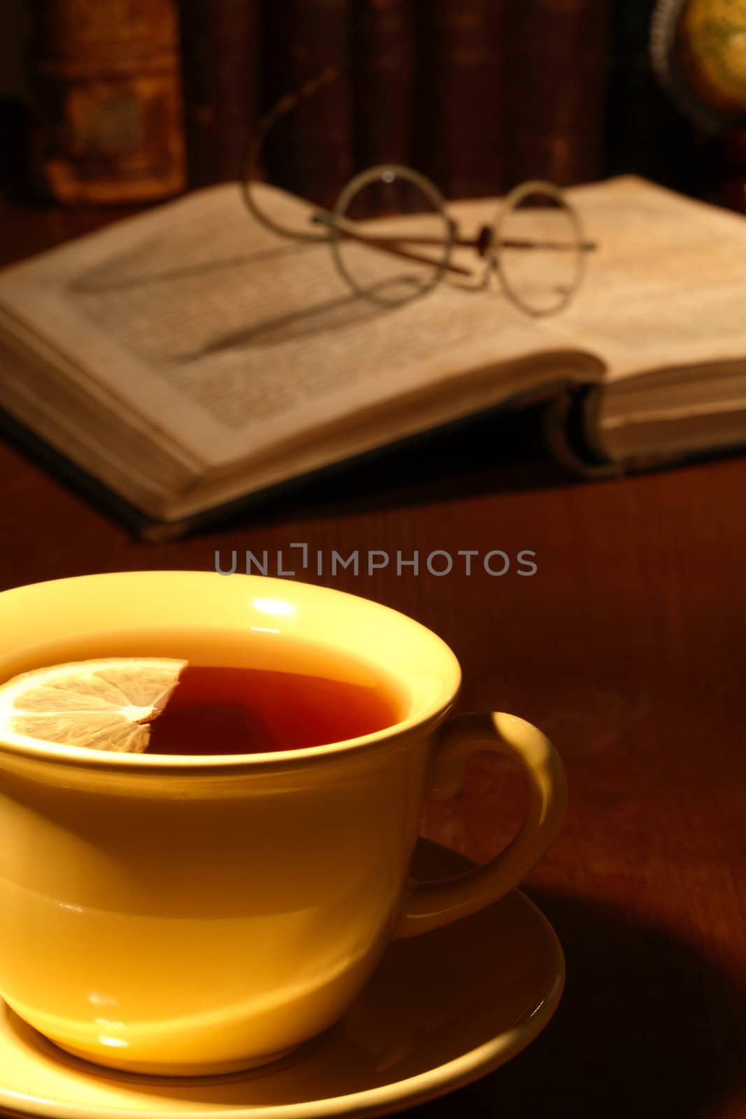 Vintage still life with cup of tea on background with old books and spectacles