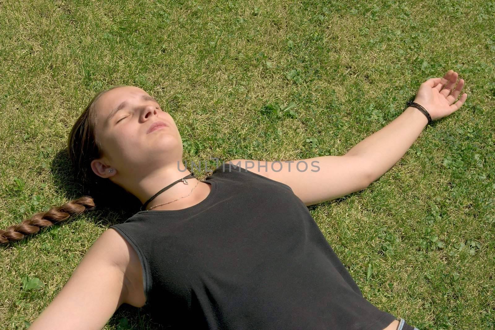 Girl laying in the green grass with eyes closed