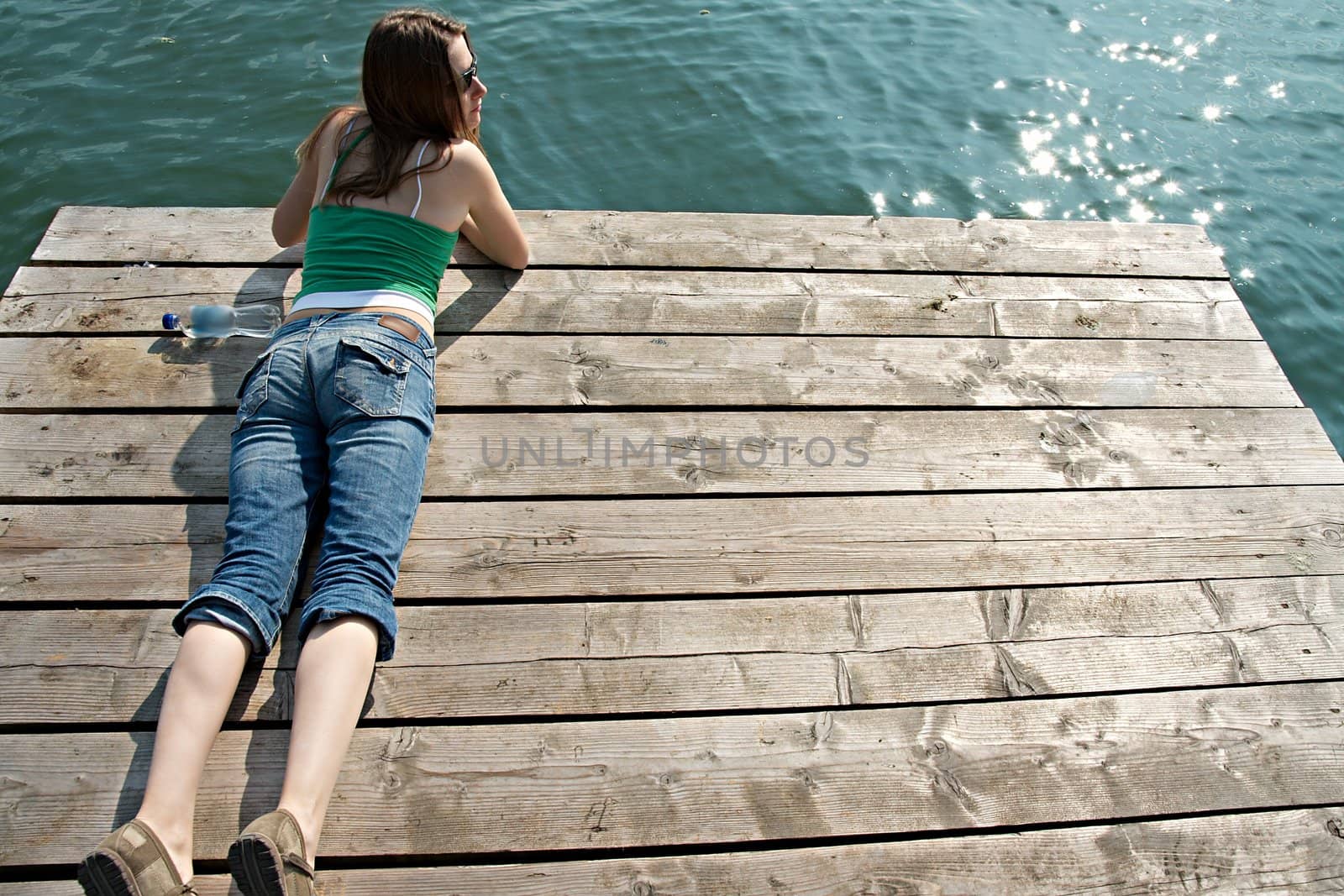Girl relaxing on a pier at a lake in summer