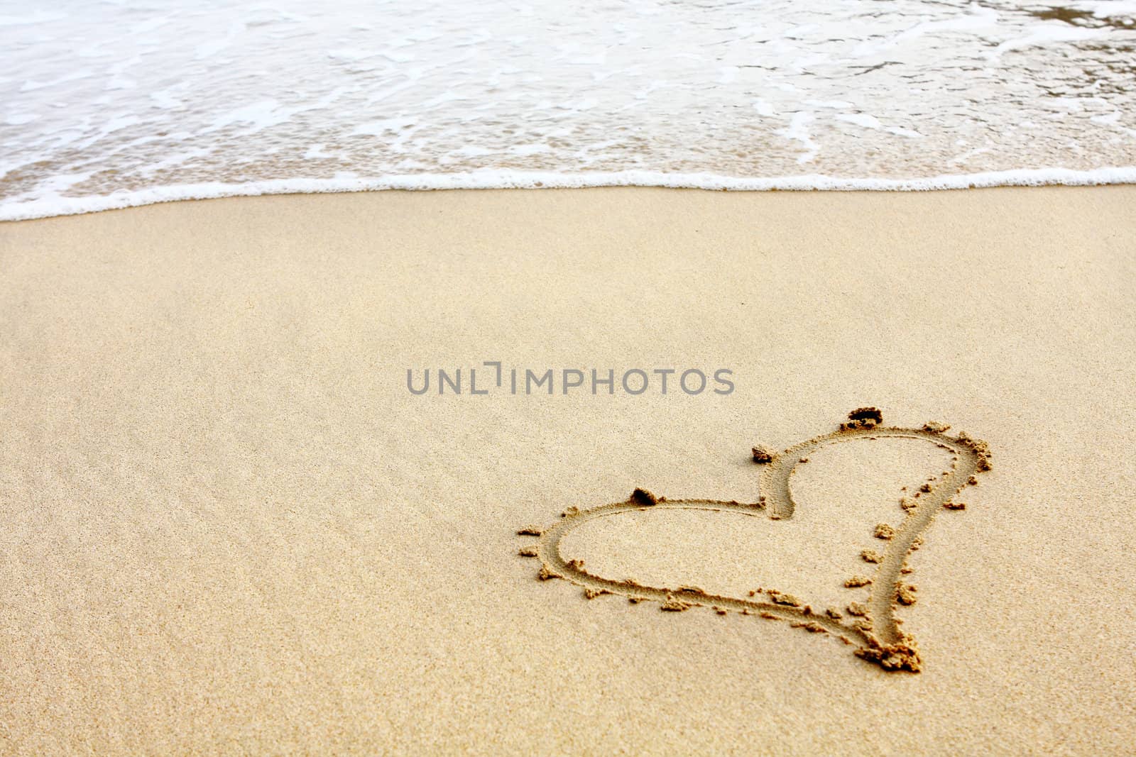 hearts drawn in the sand with seafoam and wave