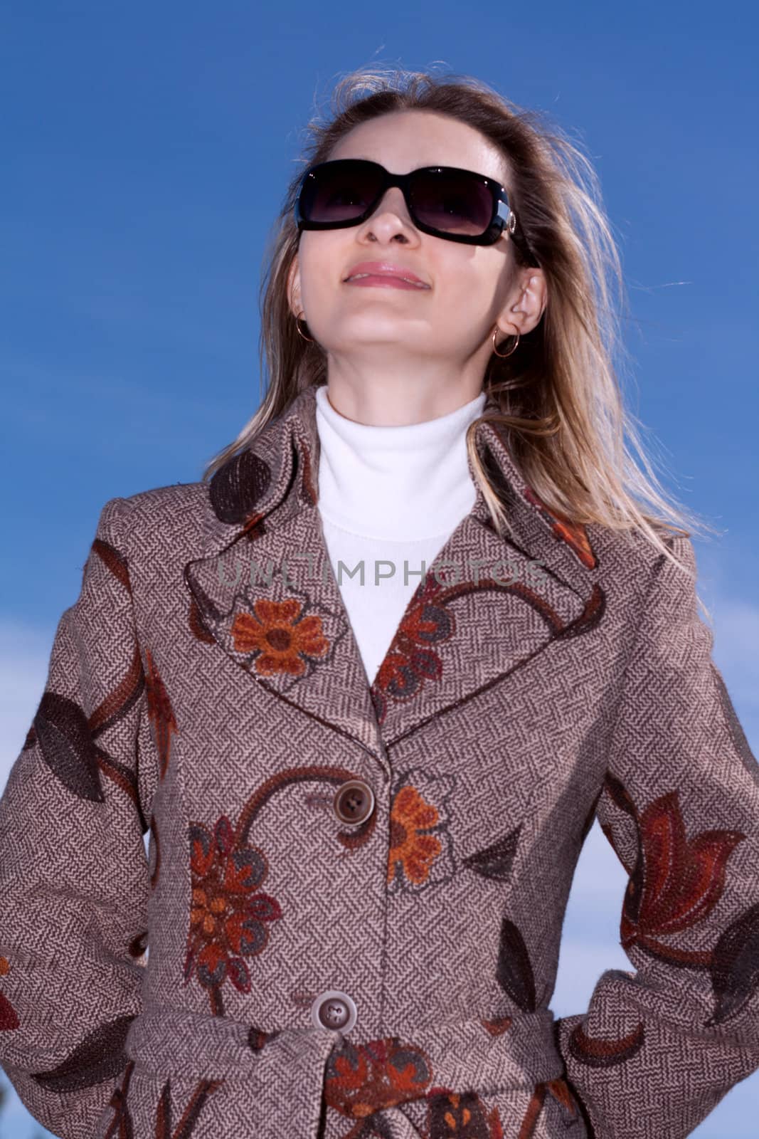 Pretty woman on background blue sky in sun-protective spectacles