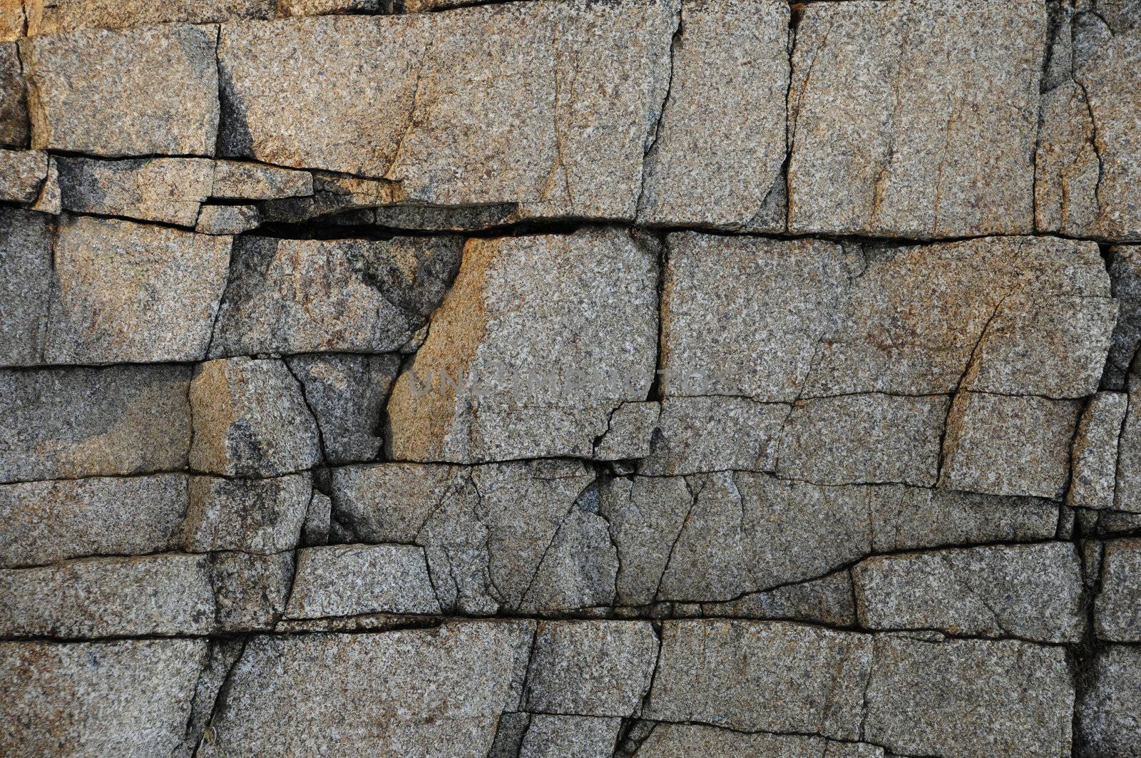 Deeply cracked granite rock surface texture