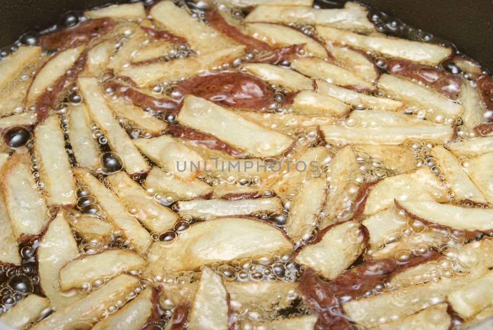 An order of french fries cooking in some oil.