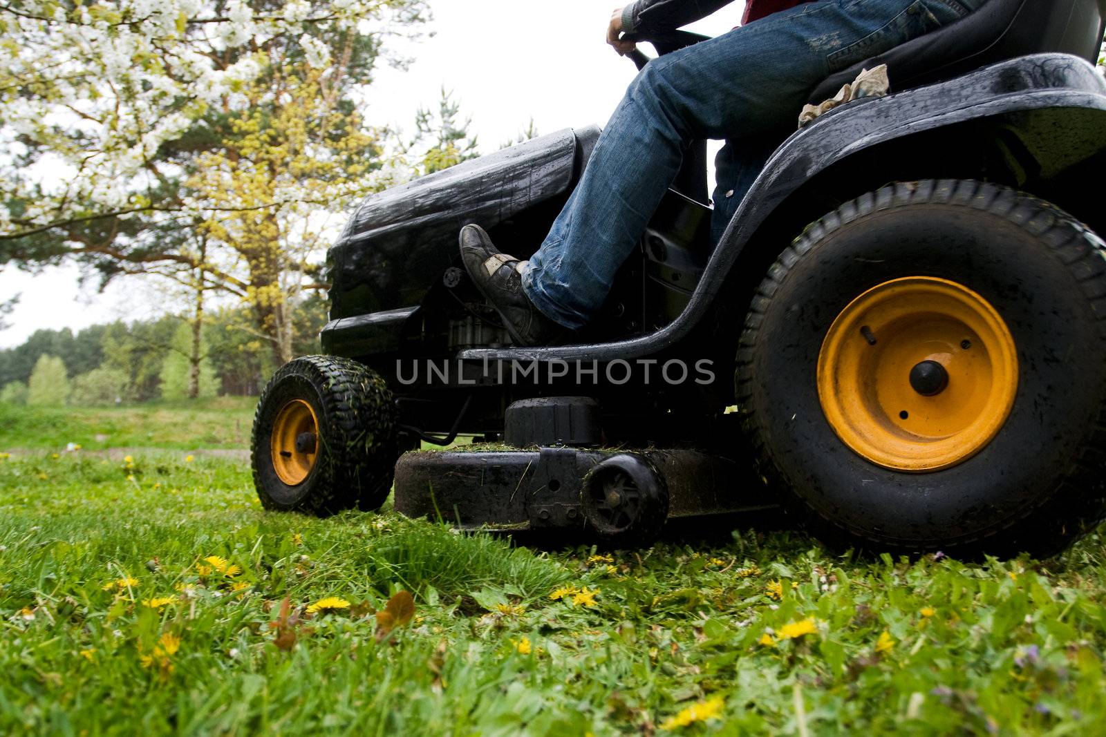 Worker mowing with black riding lawn mower