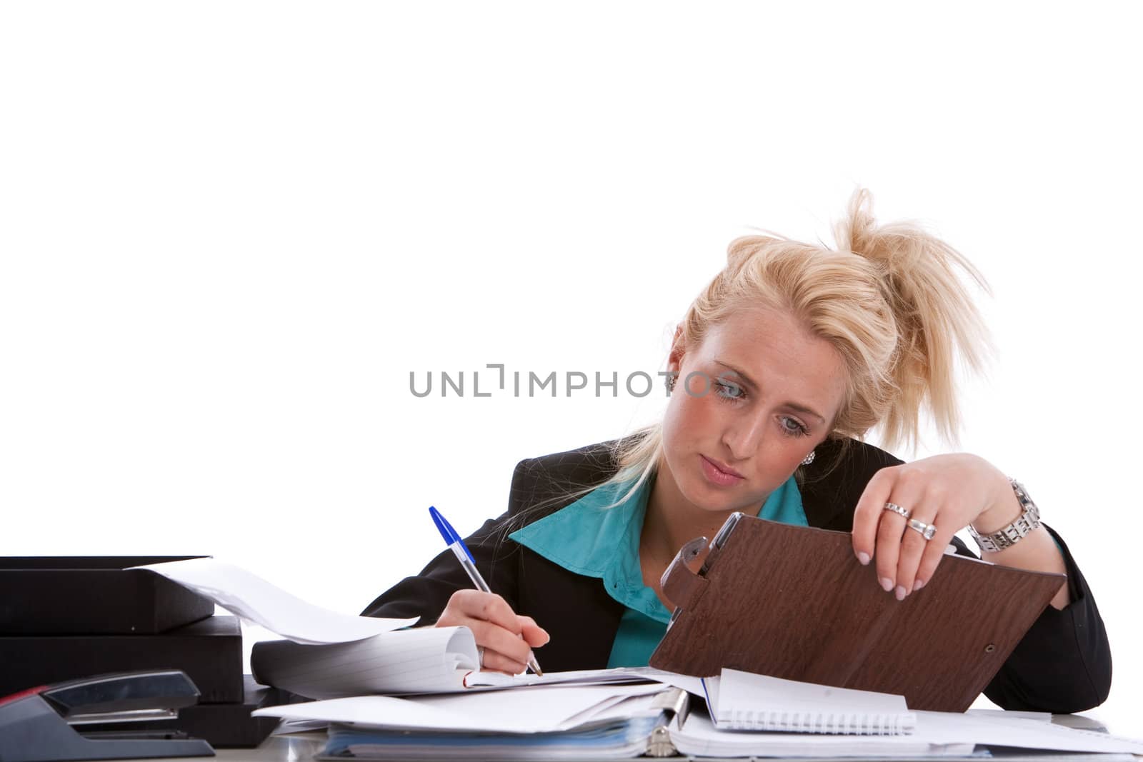 Young businesswoman with her desk piled with papers looking unhappy
