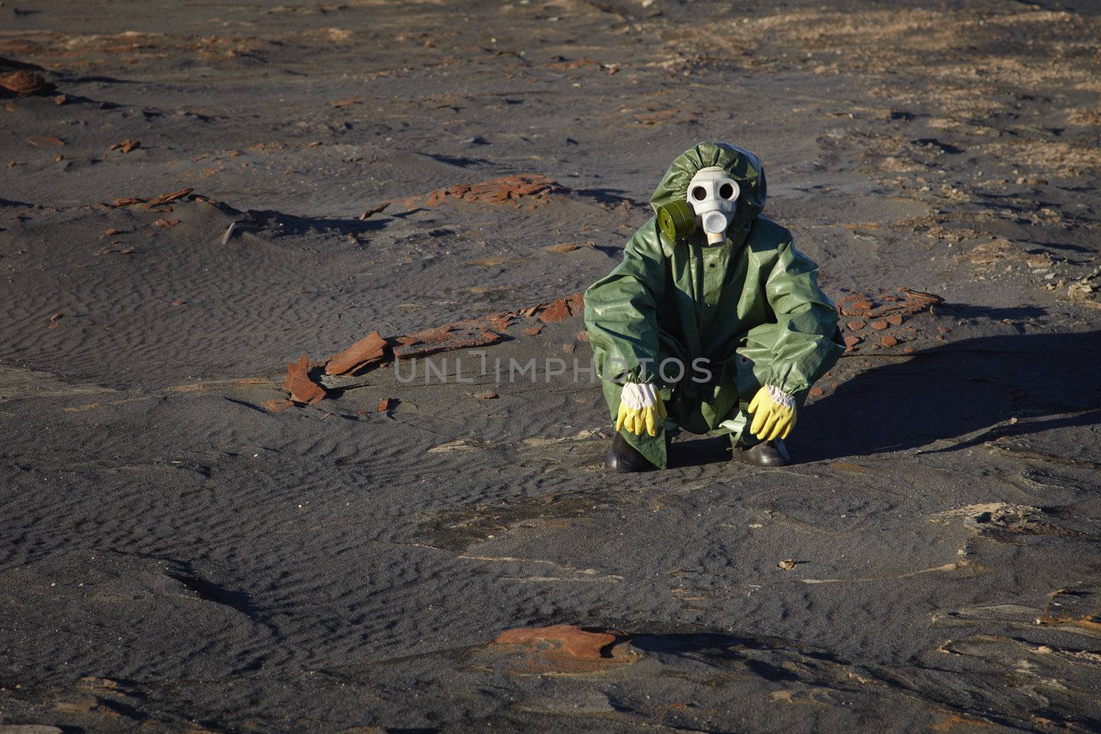 A man in protective clothing sitting in the desert
