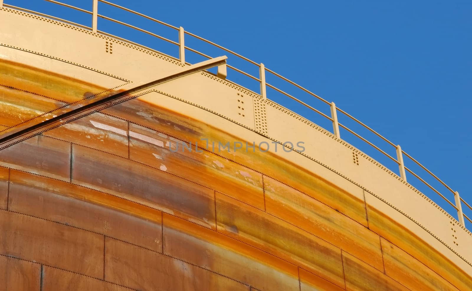 rusting gas storage facility structure against blue sky