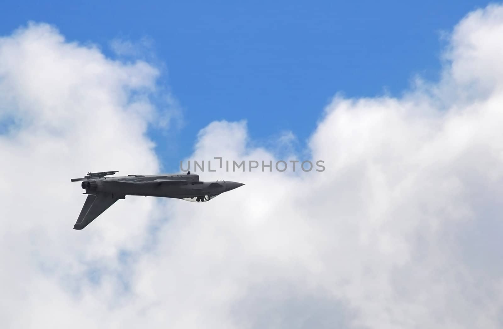 inverted military jet against cloudy blue sky