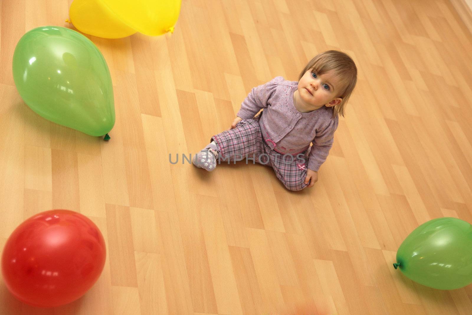 Small child sits in the middle of many colorful balloons, Copy Space
