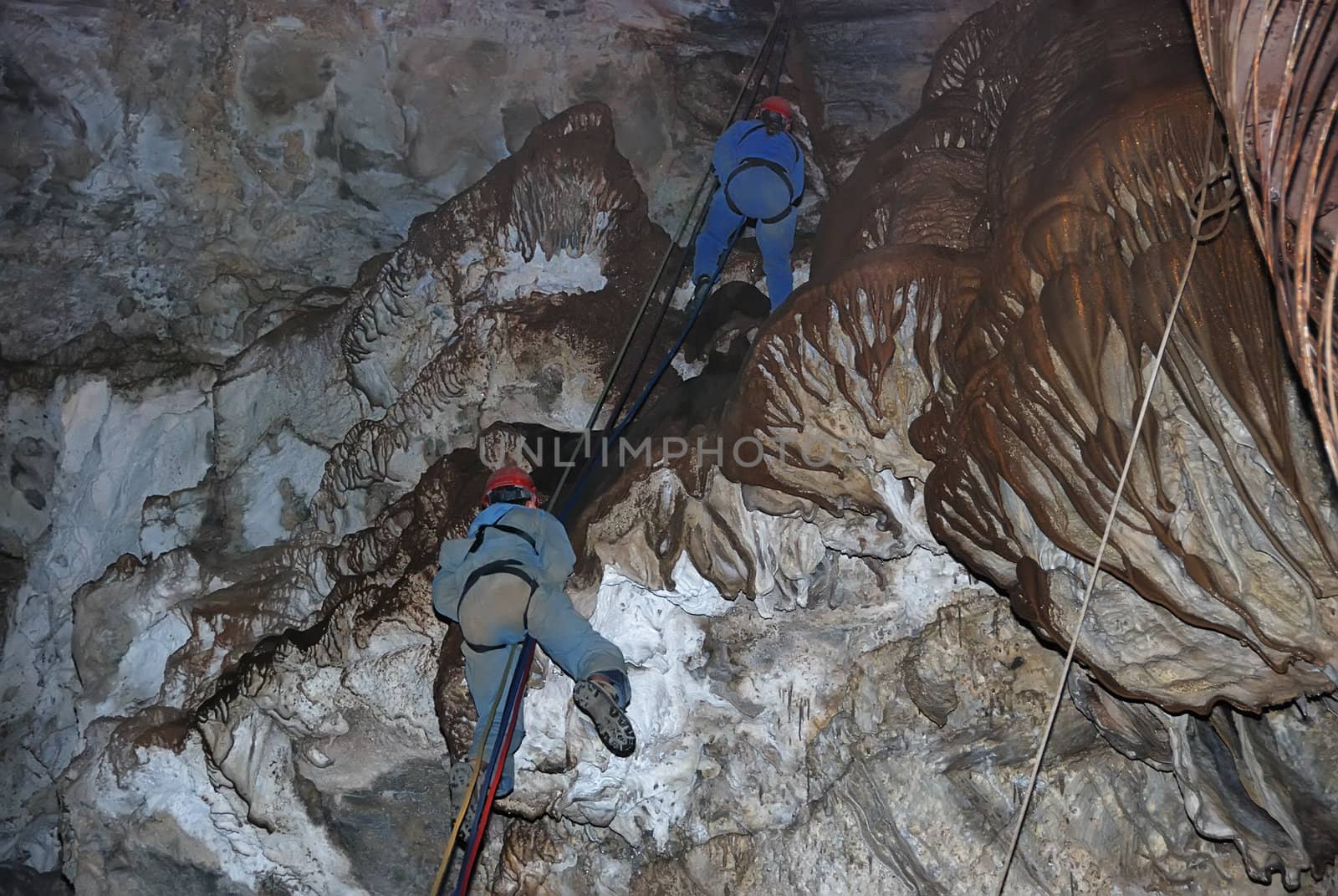 Two climbers on a rope in a cavern.