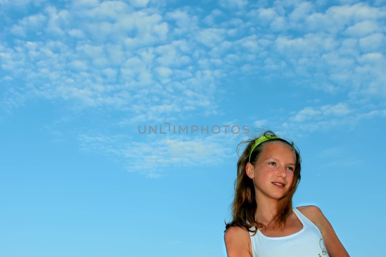 Teenage girl on the background of blue sky with clouds