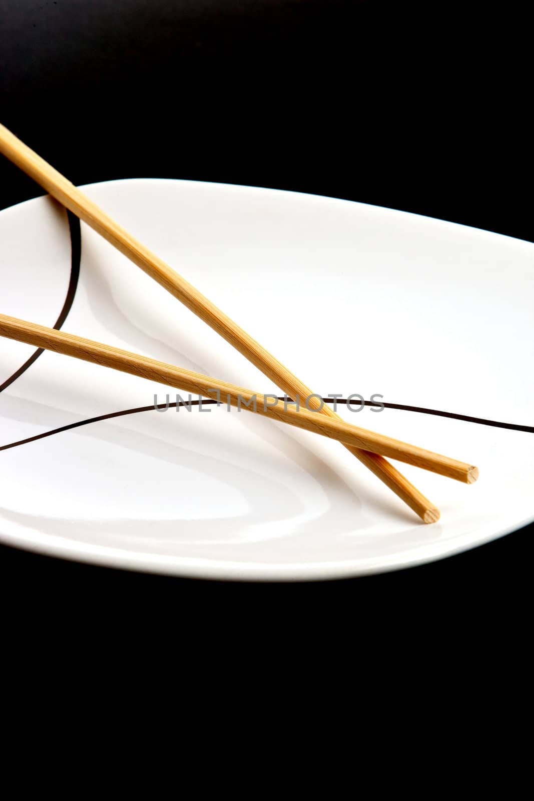 Wood chopsticks and asian style plate against black background