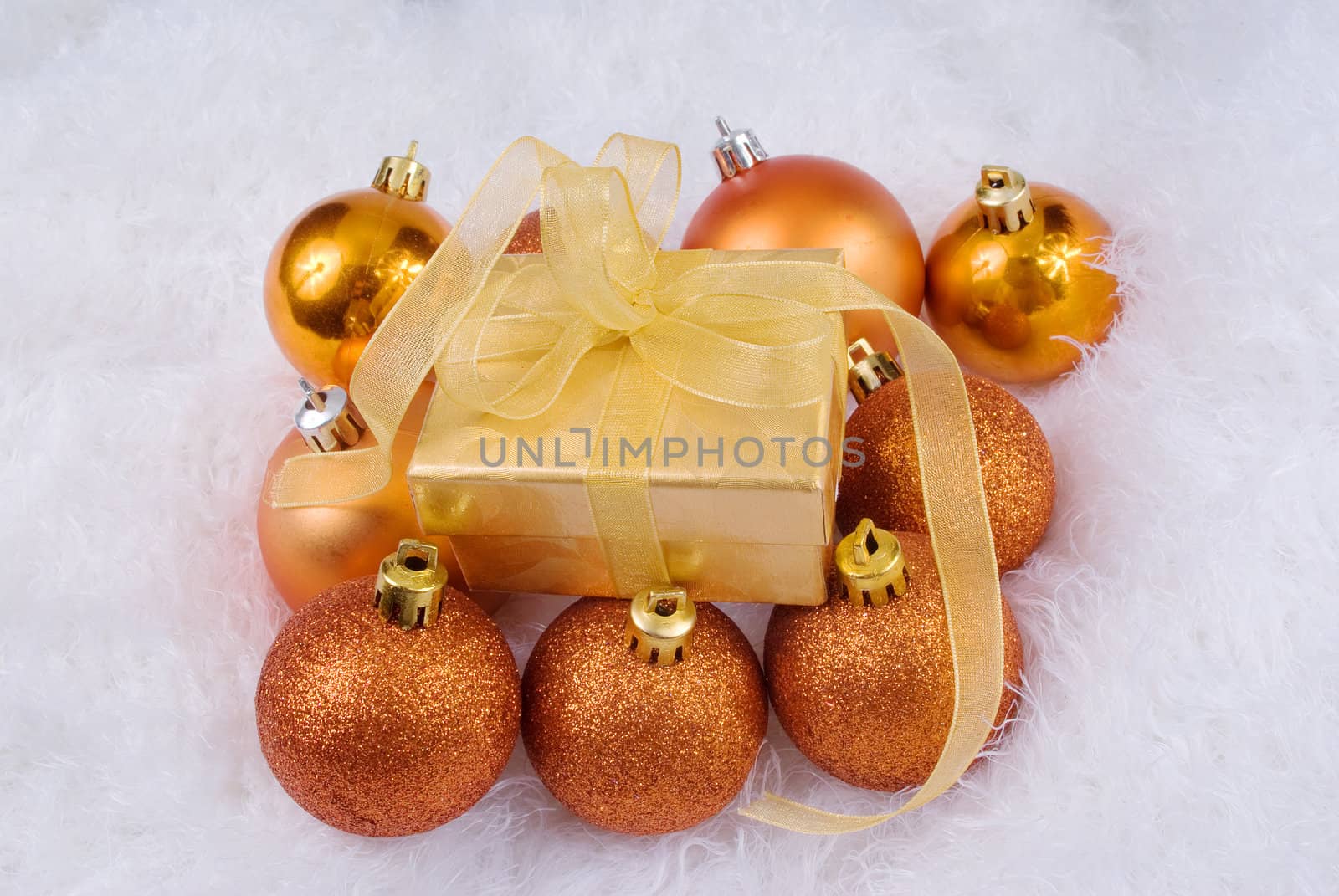 Christmas spheres and golden box on the white fur
