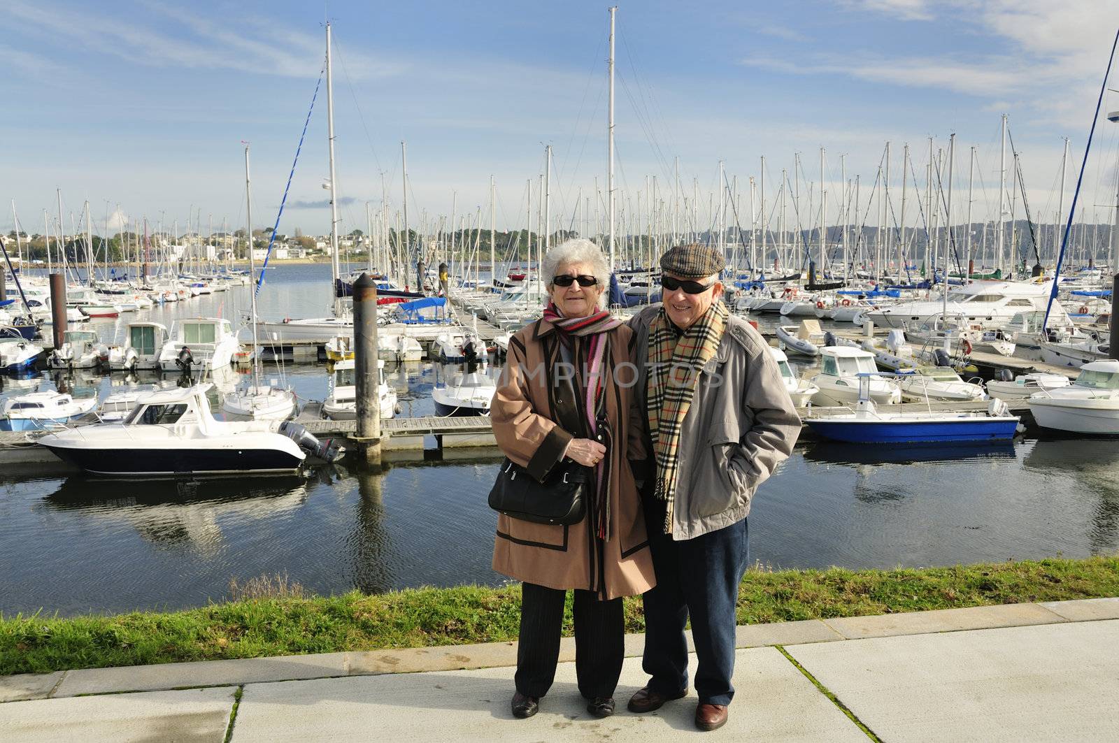 Happy old french couple walking together at the yacht harbor of Brest in Brittany, France