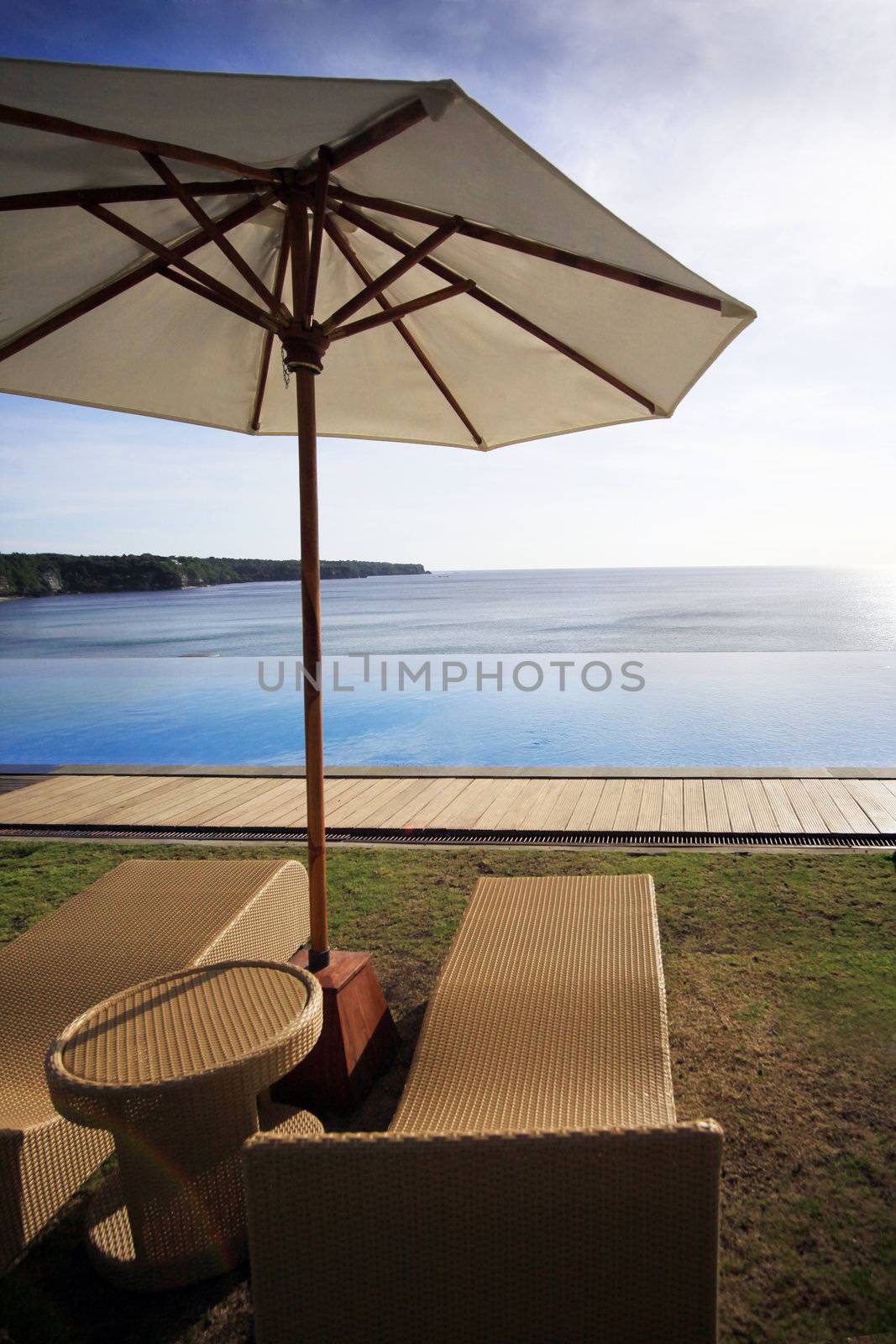 Wicker chairs on a Dreamland beach. The edge of pool merges with ocean