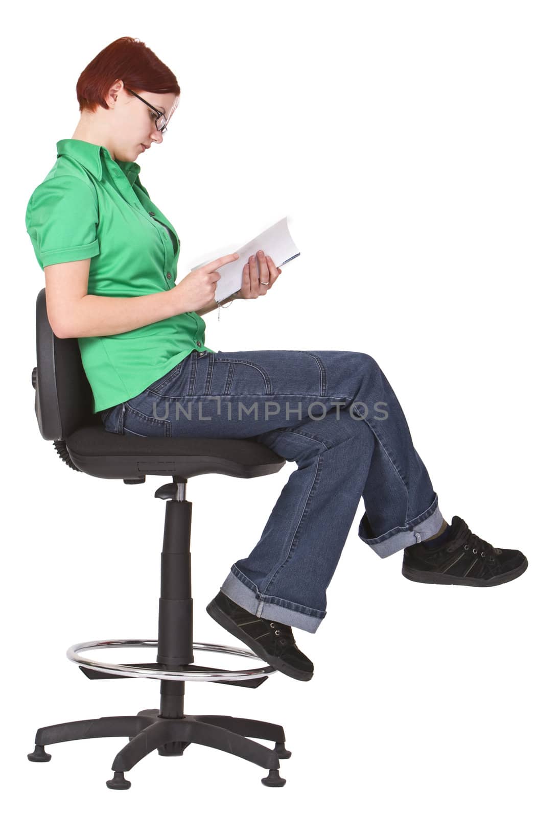 Redheaded girl sitting on a high chair and reading a book.