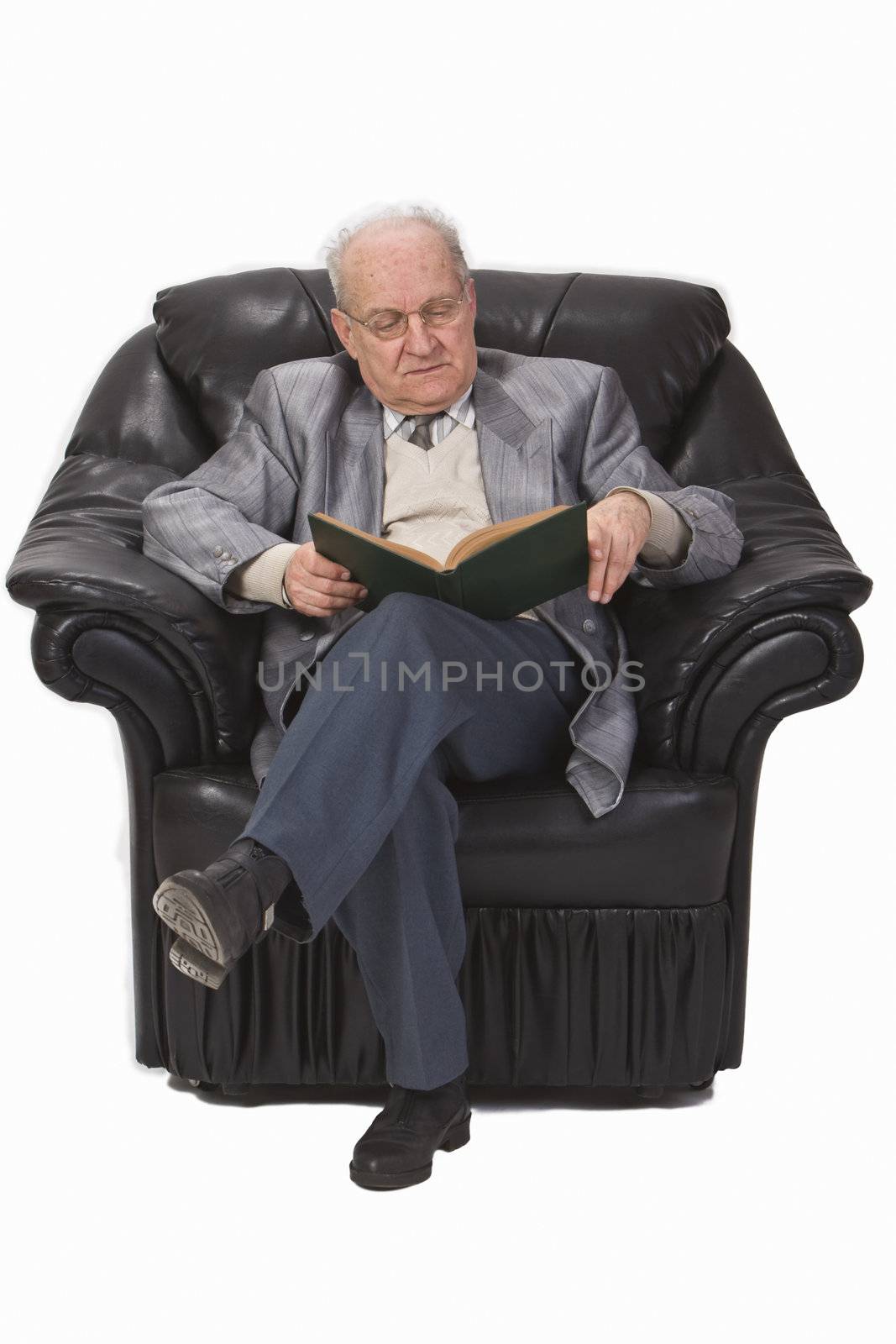 Senior man sitting in an armchair and reading a book.Shot with Canon 70-200mm f/2.8L IS USM