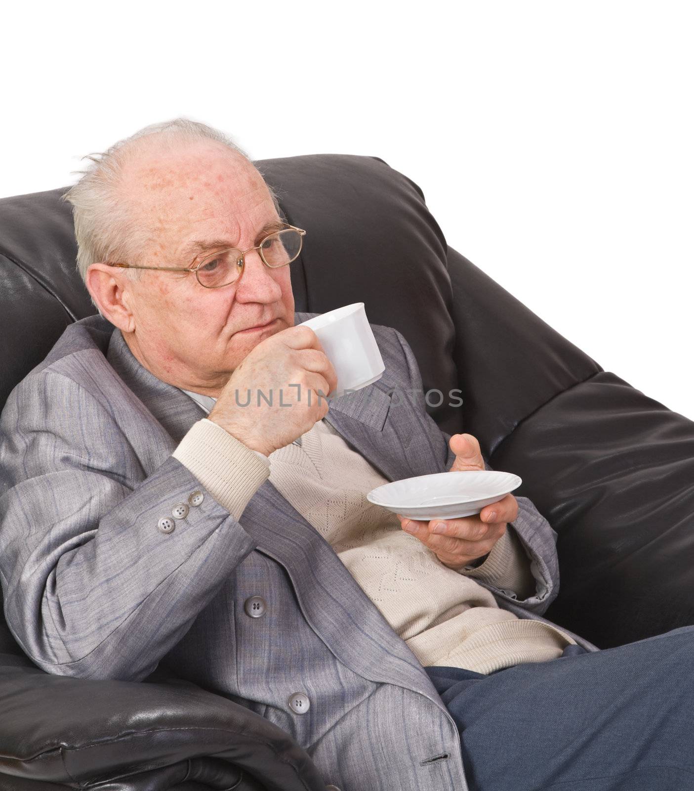 Senior man drinking a cup of tea in his office armchair.