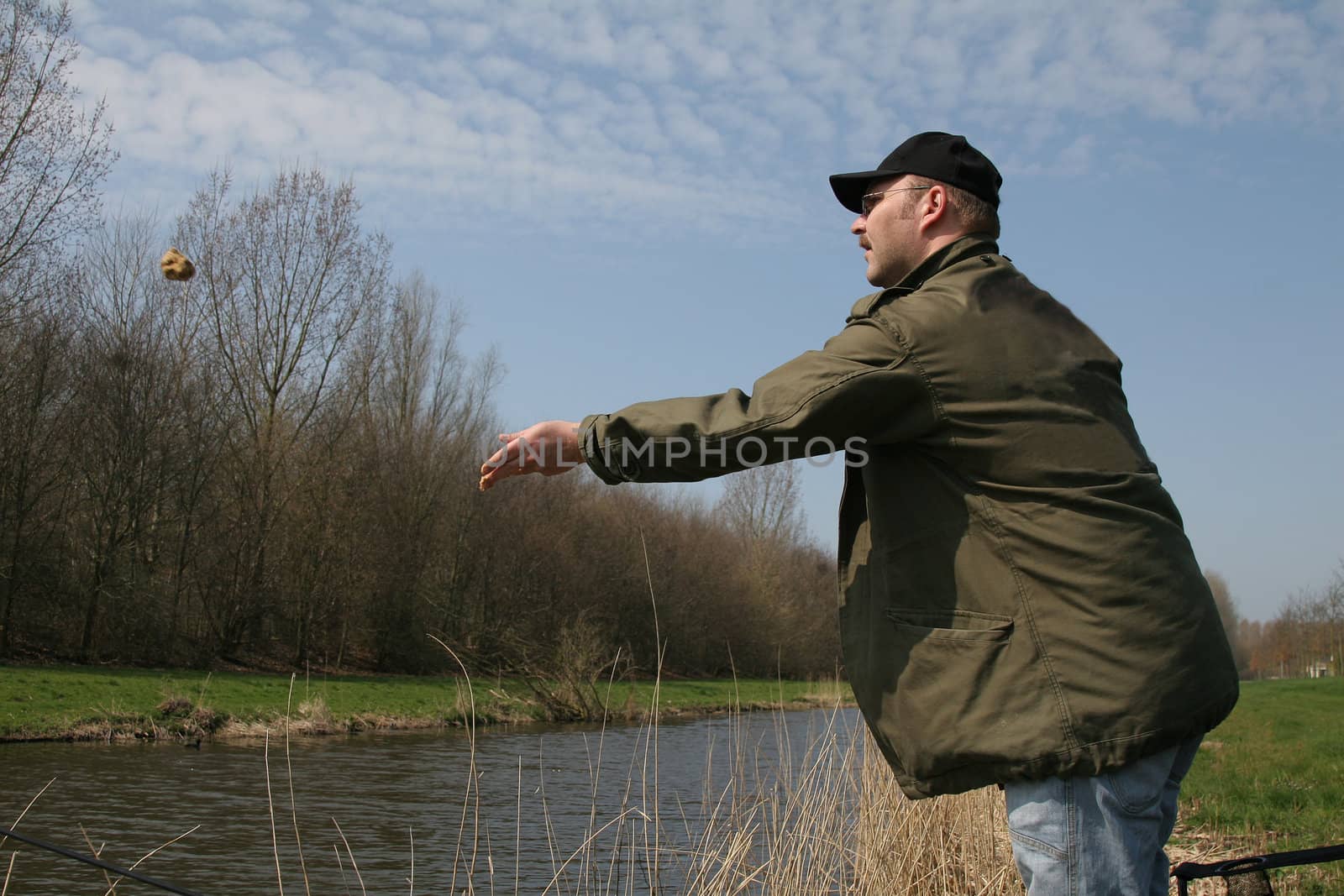 Fisherman throwing a feeding ball into the water