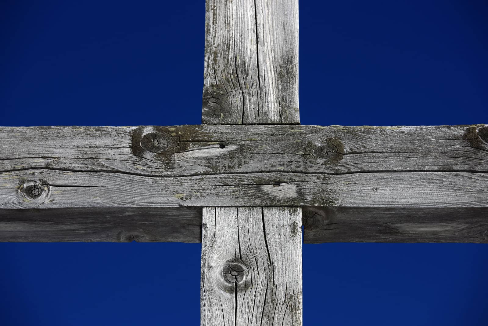 Part of a weathered wood cross on blue sky 


